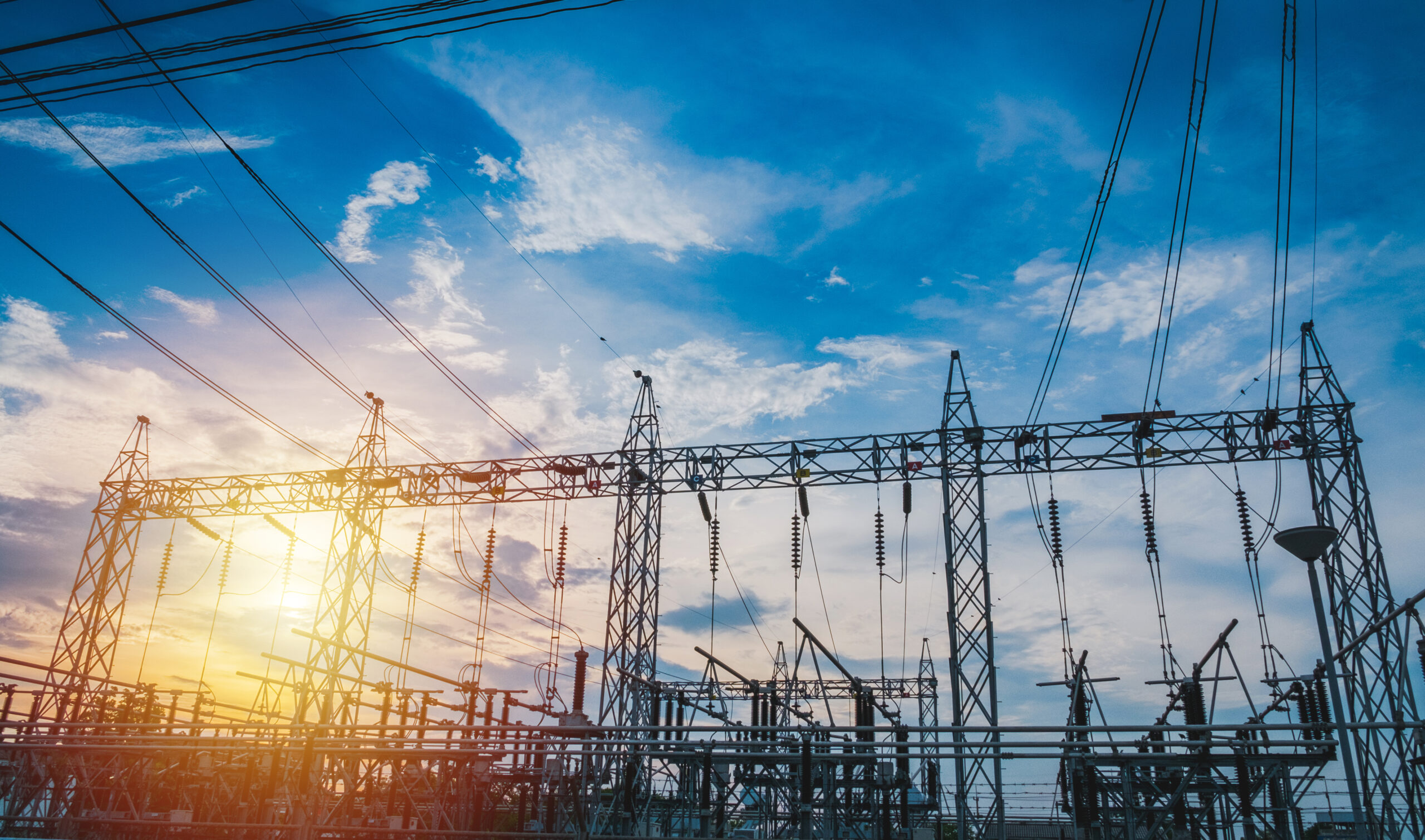 Sunset behind substation towers with blue sky.